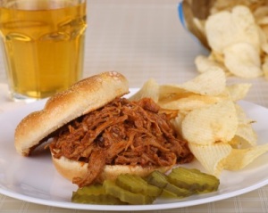 BBQ pulled pork sandwich with pickles and potato chips